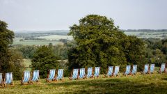 A long line of striped blue and white deckchairs are positioned on top of a hill with a view of the rolling countryside at Manor Farm, Droxford.