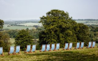 A long line of striped blue and white deckchairs are positioned on top of a hill with a view of the rolling countryside at Manor Farm, Droxford.