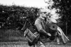 Black and white photo of a man carrying blankets and supplies.