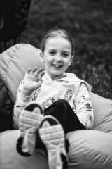 A young girl smiles and waves to the camera.