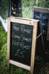 Photograph of a chalkboard with the words "Free Range Locally Sourced Hog Roast £5"