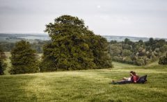 Photograph of a young couple relaxing on a large bean bag in the middle of a field.