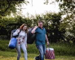 Photograph of a smiling couple carrying blankets and supplies.