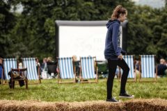 A teenage girl walking on the top of a row of hay bales